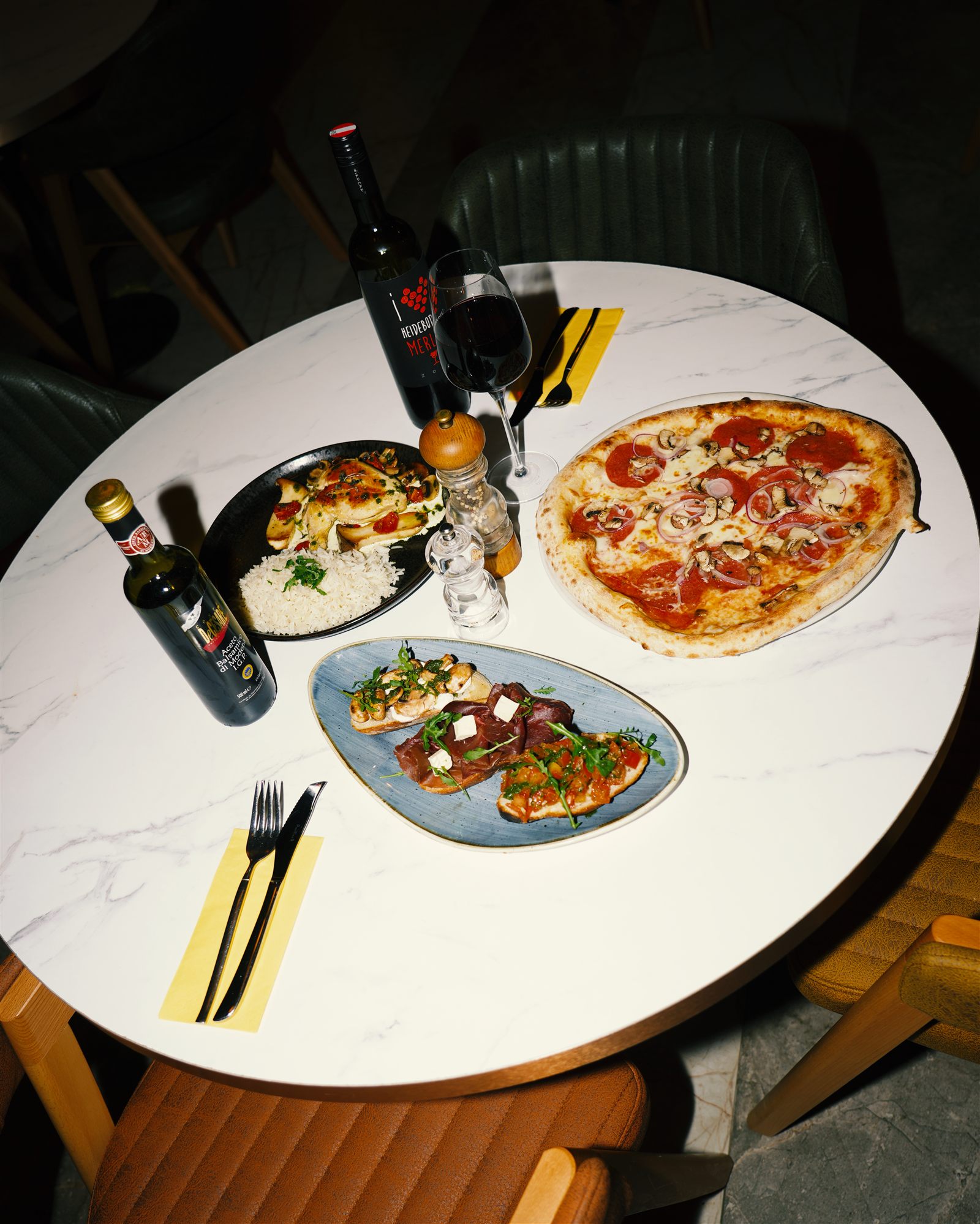 Gedeckter Marmortisch mit Pizza, Antipasti und Wein