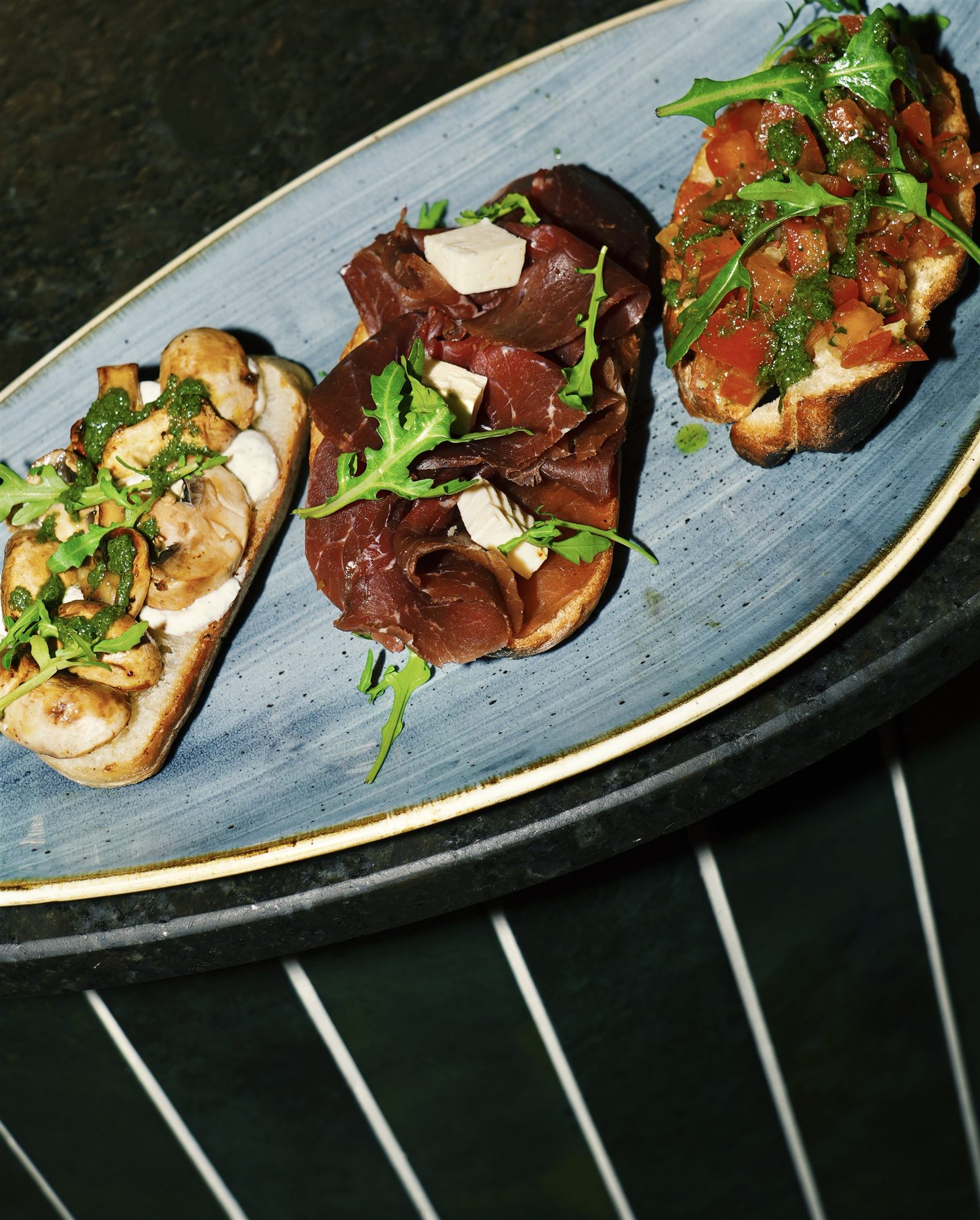 Bruschetta-Trio auf blauem Teller